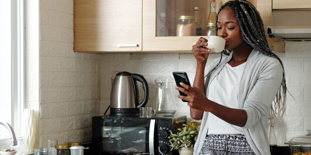 Moradora utilizando aplicativo eCondos no celular em ambiente residencial, representando praticidade, autonomia e satisfação do usuário com a rotina do condomínio.